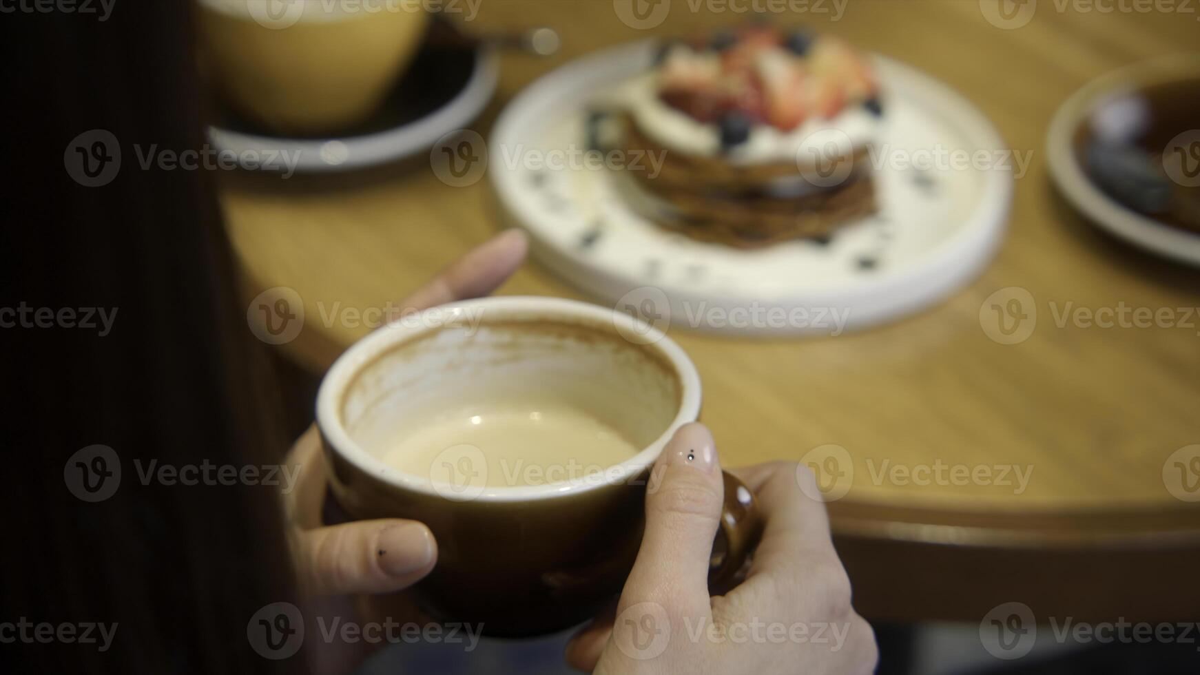 Close-up of beautiful woman having lunch in cafe with coffee and dessert. Stock footage. Woman drinks coffee with beautiful dessert in cafe. Beautiful aesthetic lunch with dessert and coffee in cafe photo