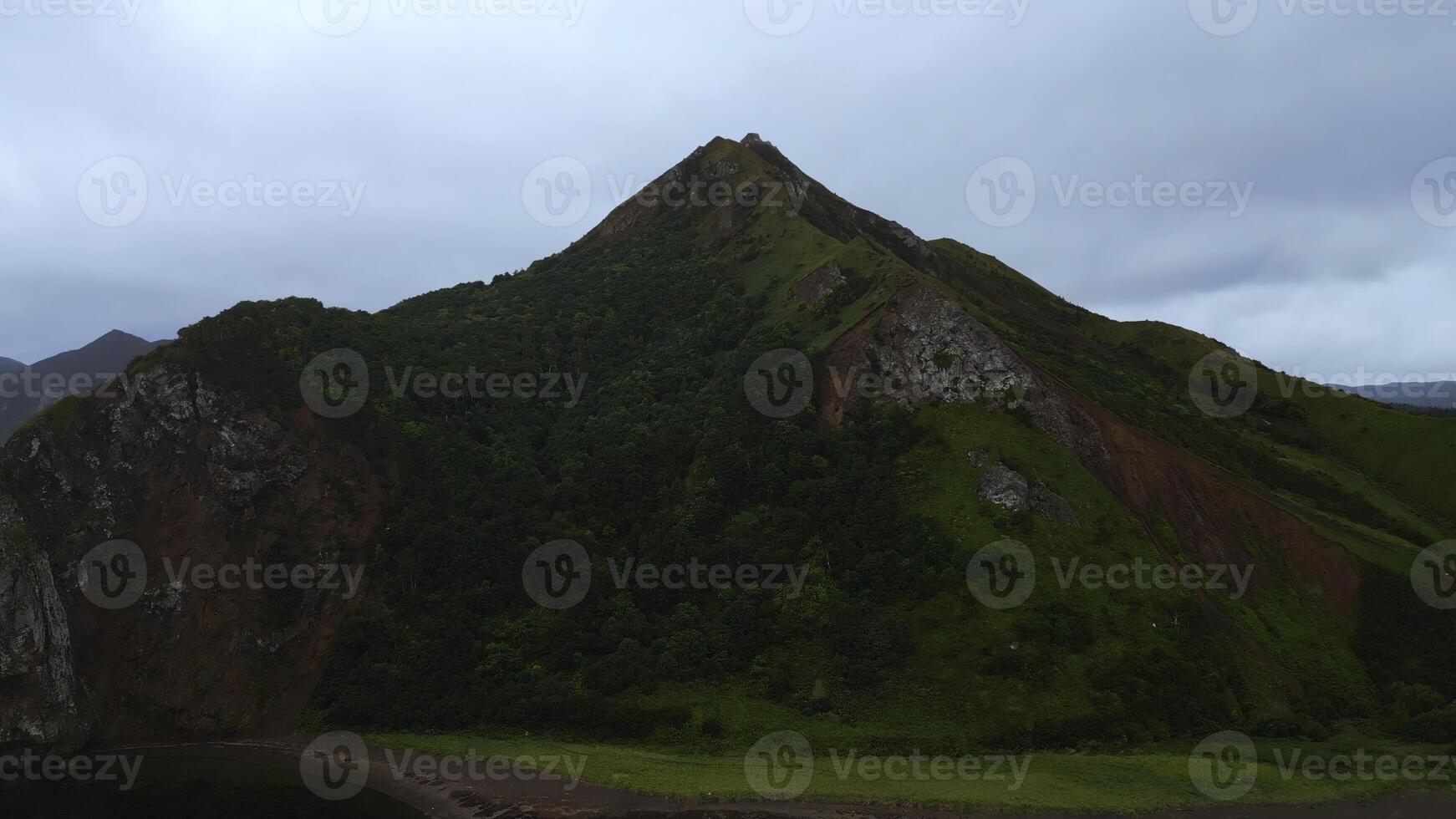 View of green mountains with forest. Clip. Top view of mountain slope with green dense forest. Amazing nature of mountains with green forest slopes on cloudy day photo