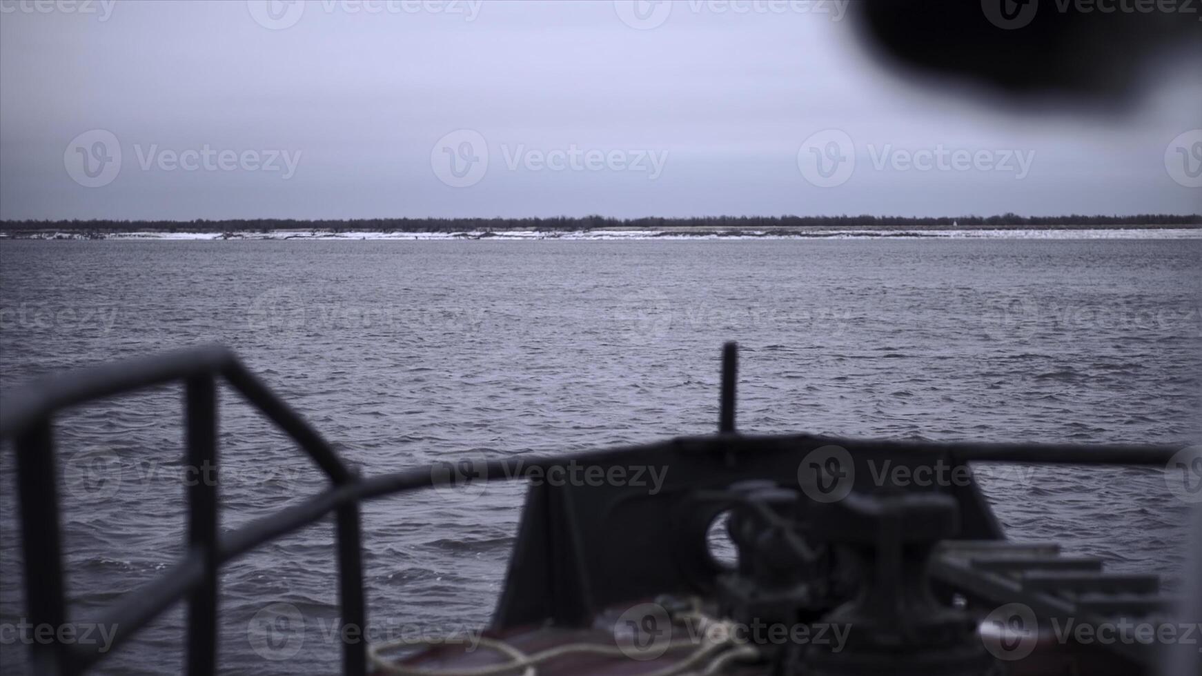 Fishing vessel on background of shore in winter. Clip. Front part of sailing ship to shore in winter. Fishing boat sails to shore on winter day photo