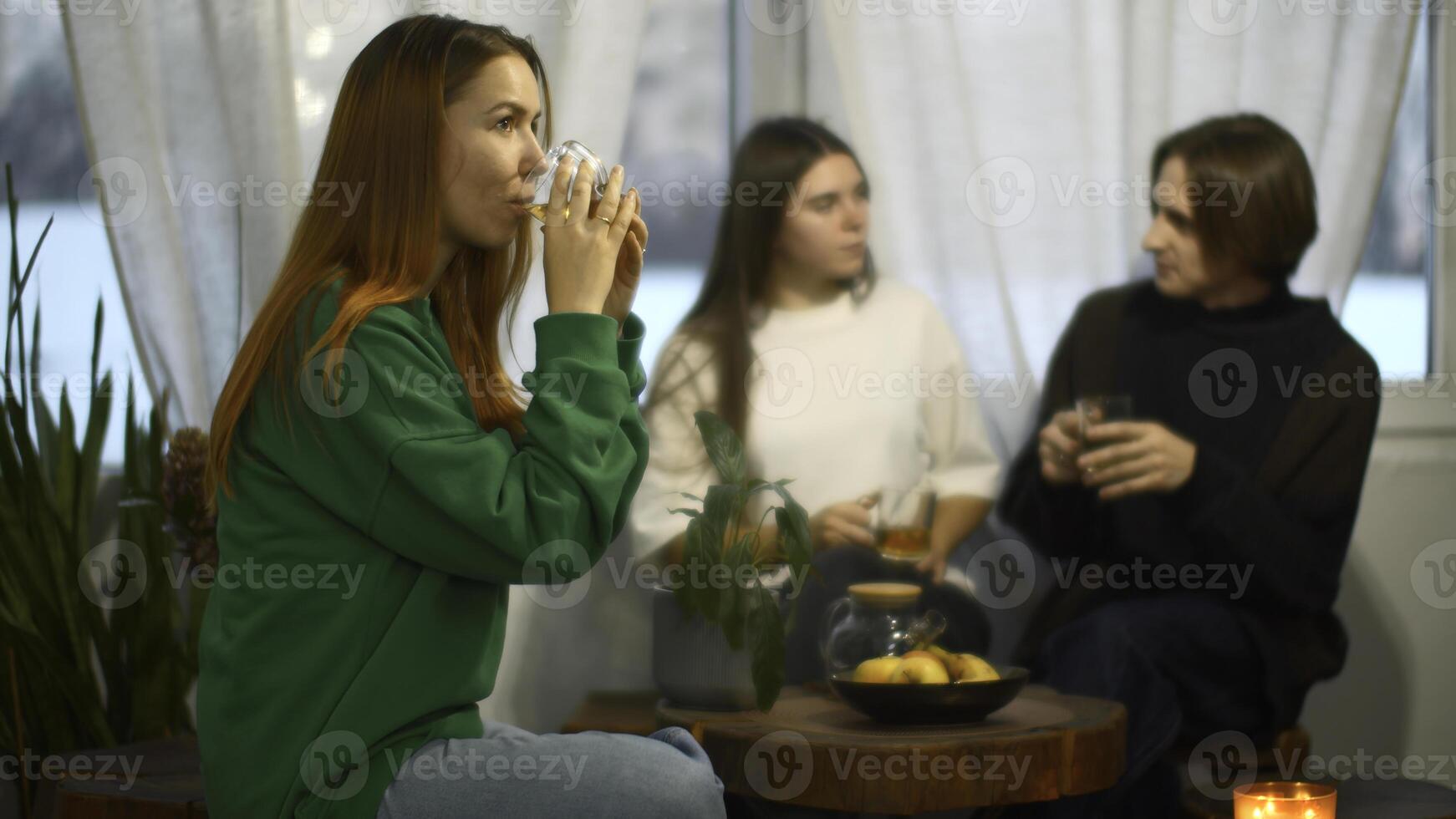 Students talk and relax in cozy cafe. Media. Beautiful young woman is drinking tea on background of talking couple. Students relax and drink tea in college cafe photo