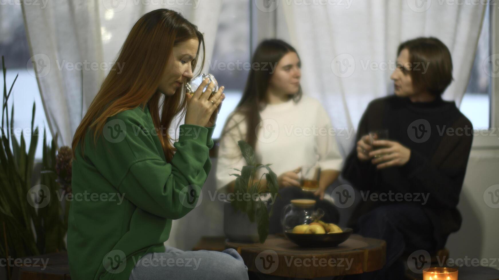 Students talk and relax in cozy cafe. Media. Beautiful young woman is drinking tea on background of talking couple. Students relax and drink tea in college cafe photo