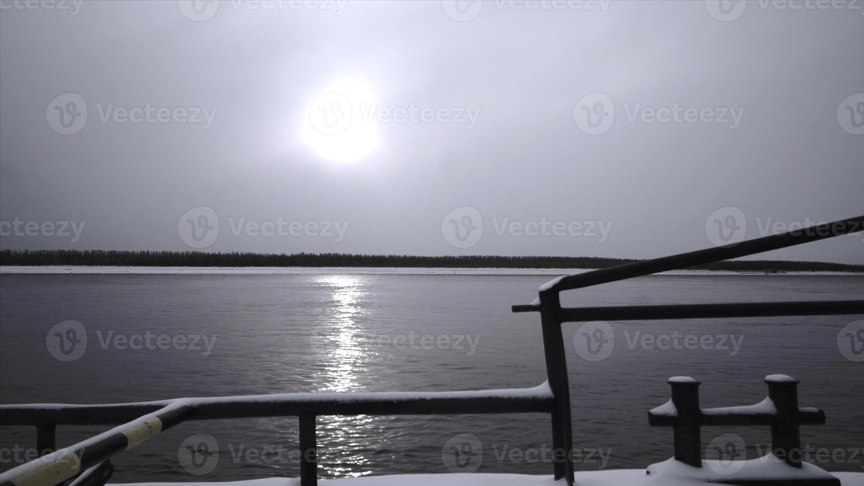 Sea vessel with snow floating on river. Clip. Sailing on sea vessel along river on winter day. Close-up of floating fishing vessel with snow on river near winter shore photo