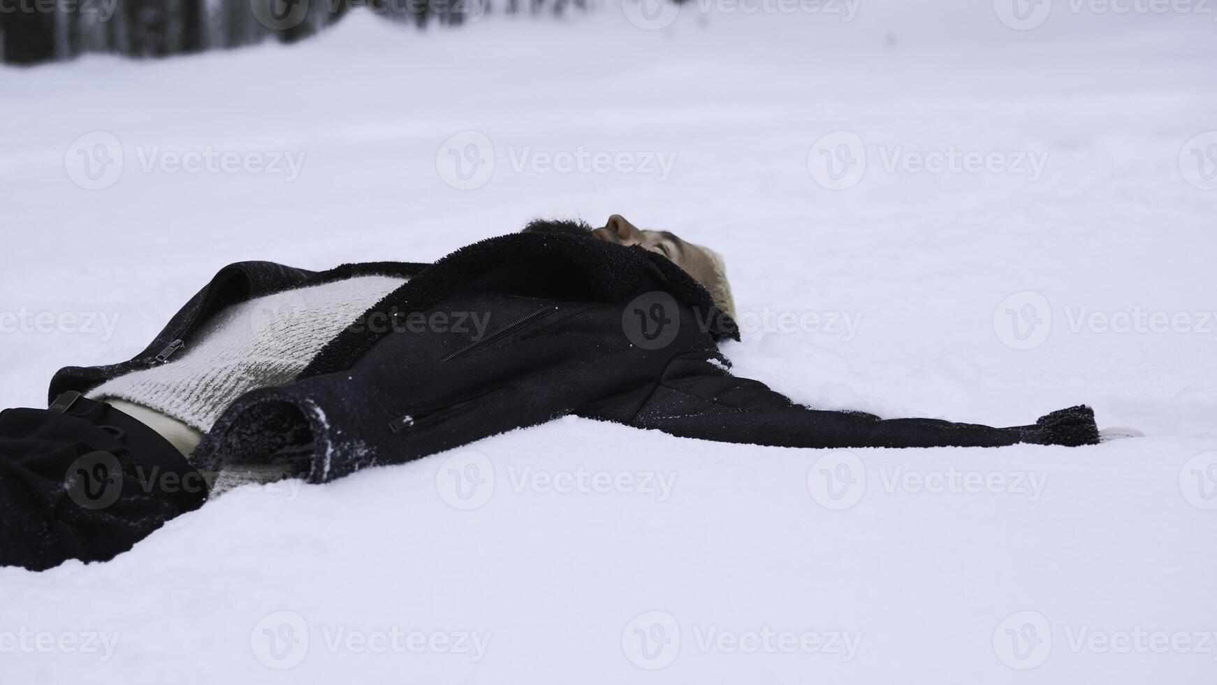 Man lies in white snow in winter. Media. Man lies and rests on winter snow in forest. Man is resting or sleeping in snow on winter day photo