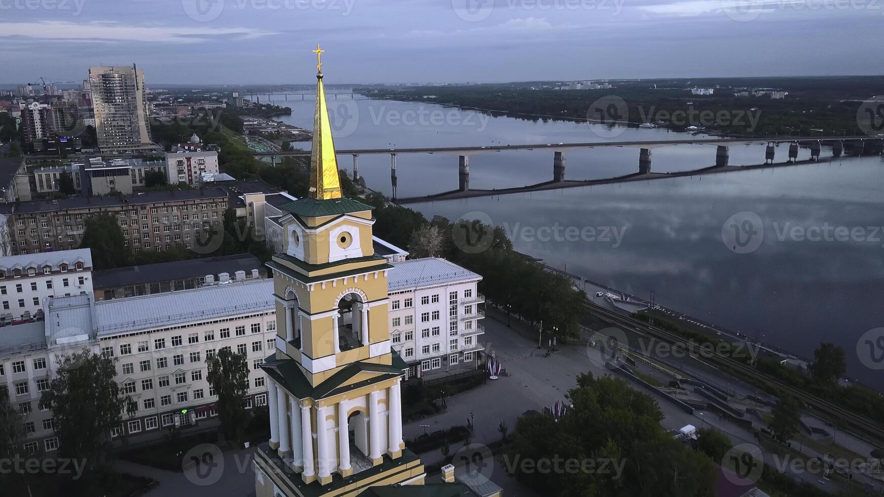 Top view of beautiful city church on river bank with bridge. Clip. Beautiful urban landscape with temple on riverbank on cloudy day. City with church on river with bridge photo
