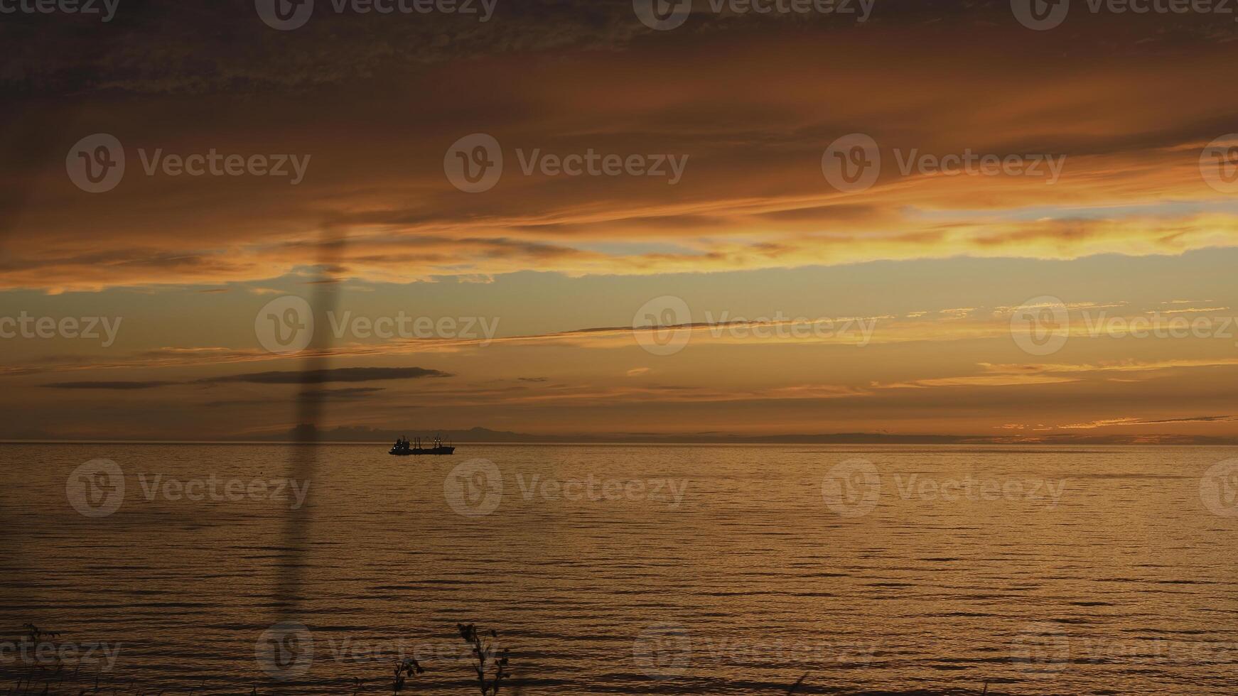 Beautiful seascape with sunset sky and ship on horizon. Clip. Magnificent view of sea sunset with red clouds and ship on horizon. Red sunset with beautiful sea and ship photo