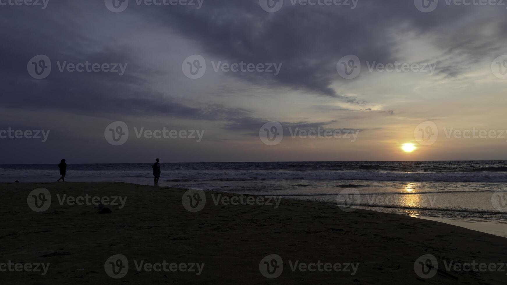 Dramatic sea sunrise on cloudy sky. Action. Wavy sand sea shoe and a couple meeting new day. photo