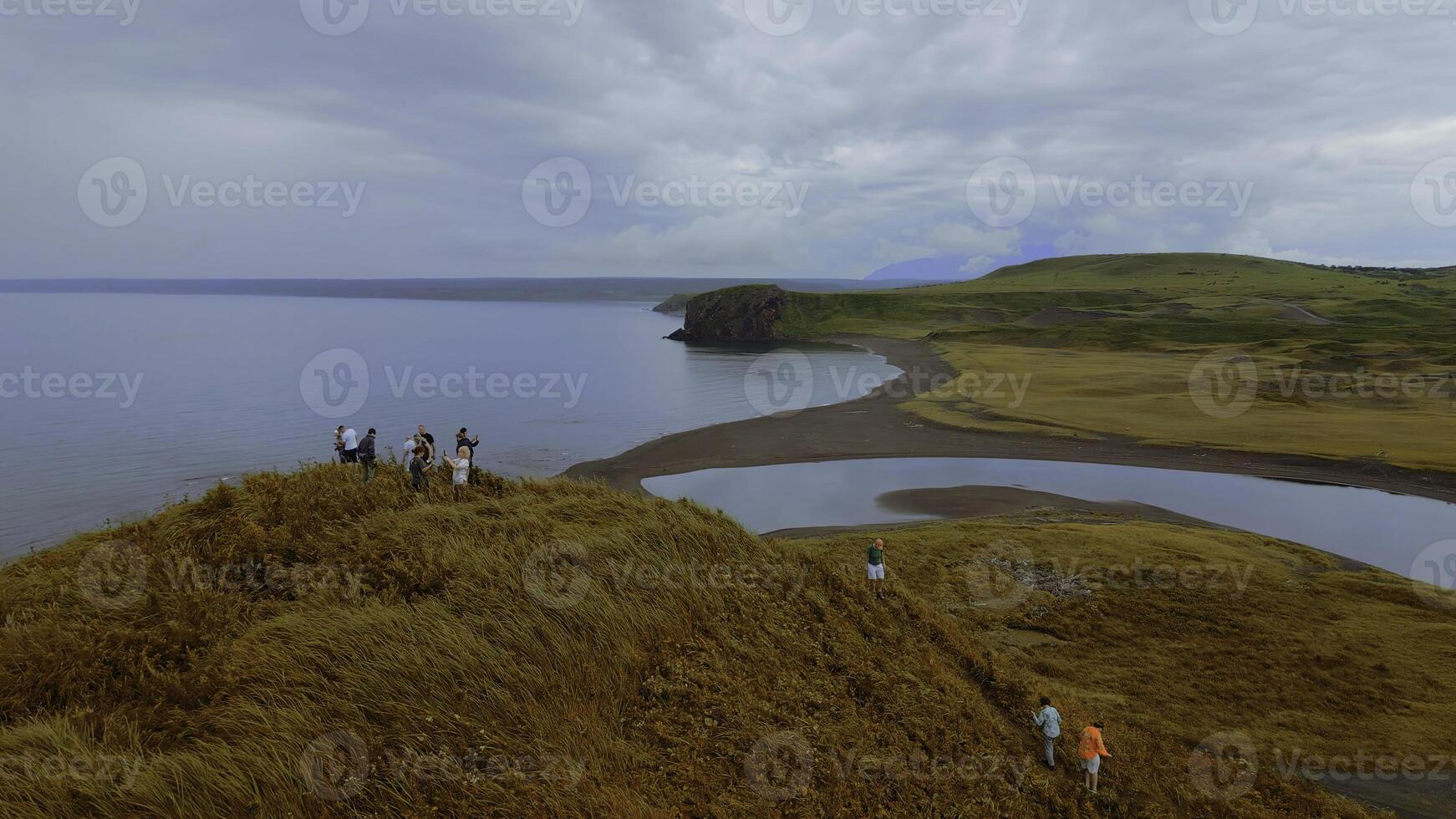 concepto de turismo, grupo de personas en el colina cima. acortar. aéreo ver de amarillo césped y el mar costa. foto