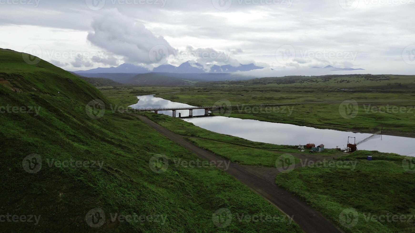 The bridge with the river and green valley as a backdrop. Clip. Aerial view of summer green valley and long narrow river. photo