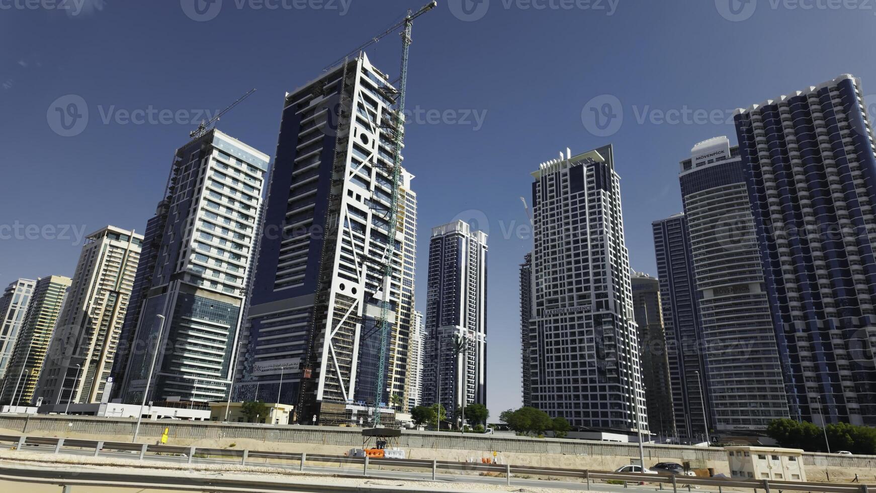 Dubai city with street and bridge with driving cars. Action. Clear blue sky and skyscrapers of the city center. photo