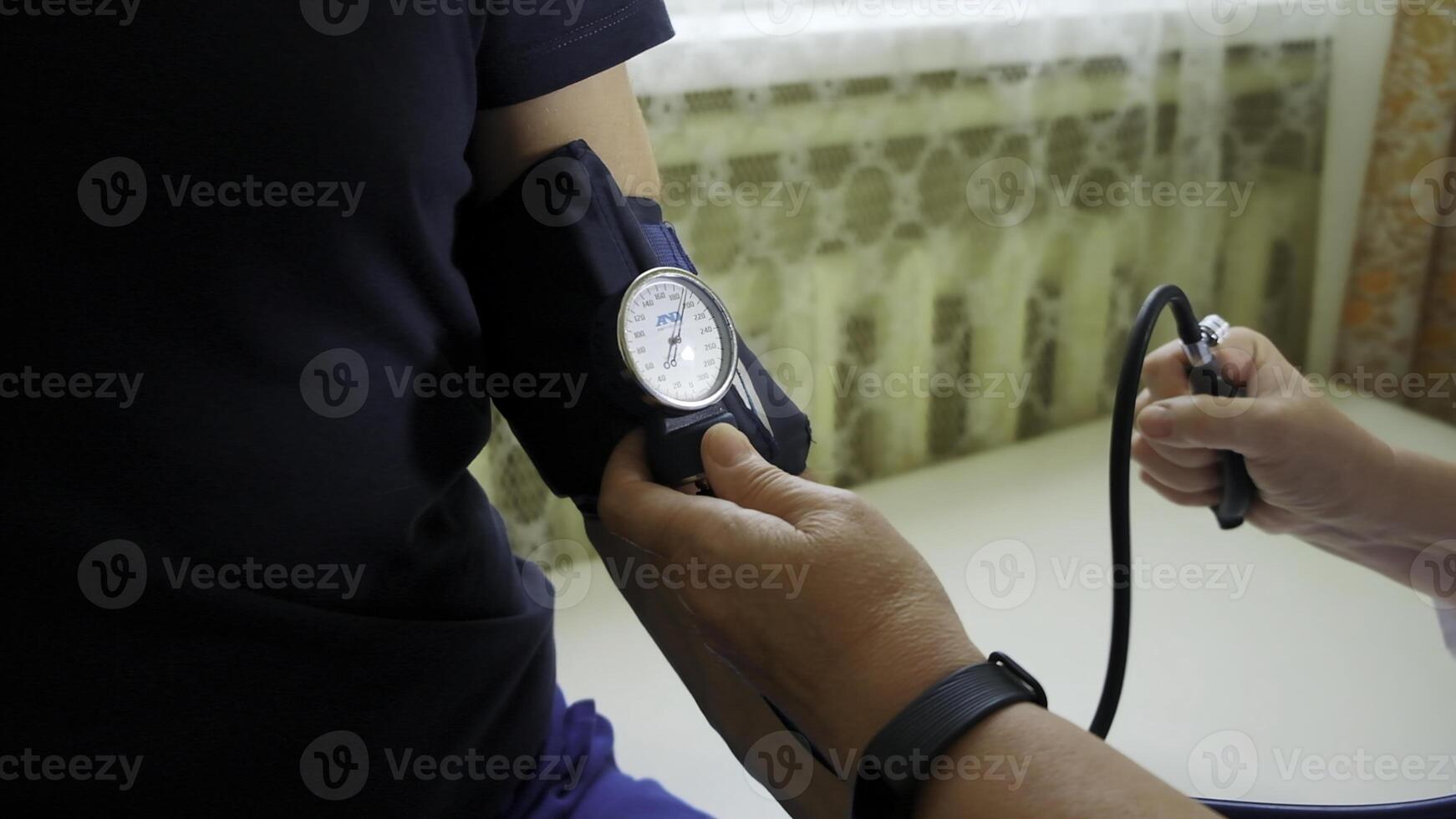 Doctor uses mechanical tonometer to check body pressure of a male patient. Clip. Concept of health care and medicine. photo