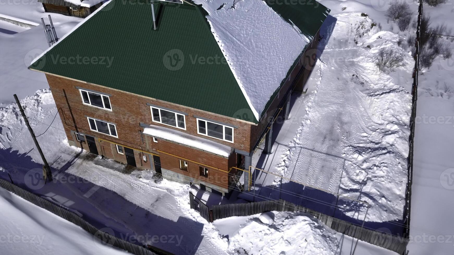 aéreo ver de pueblo en invierno, campo detalles. acortar. rojo ladrillo cabaña y menor casas, nieve cubierto suelo. foto