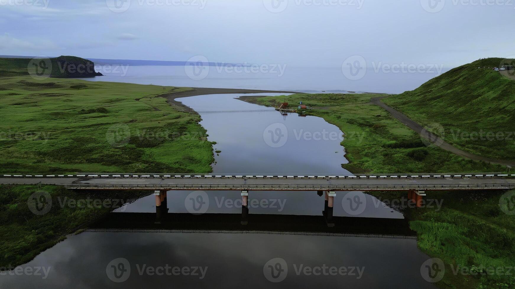 Summer aerial view of the narrow river flowing into the sea. Clip. Concrete bridge crossing calm river. photo