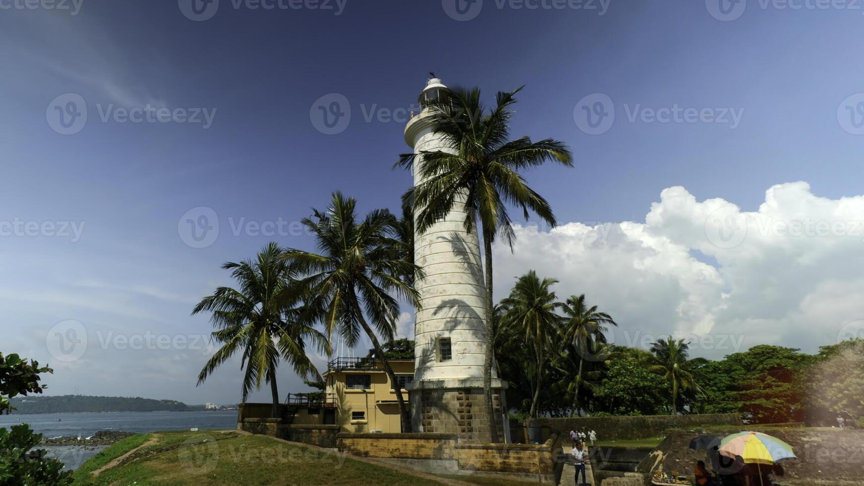 Galle Lighthouse at Galle Fort, Sri Lanka. Action. Beautiful palm trees and blue cloudy sky. photo