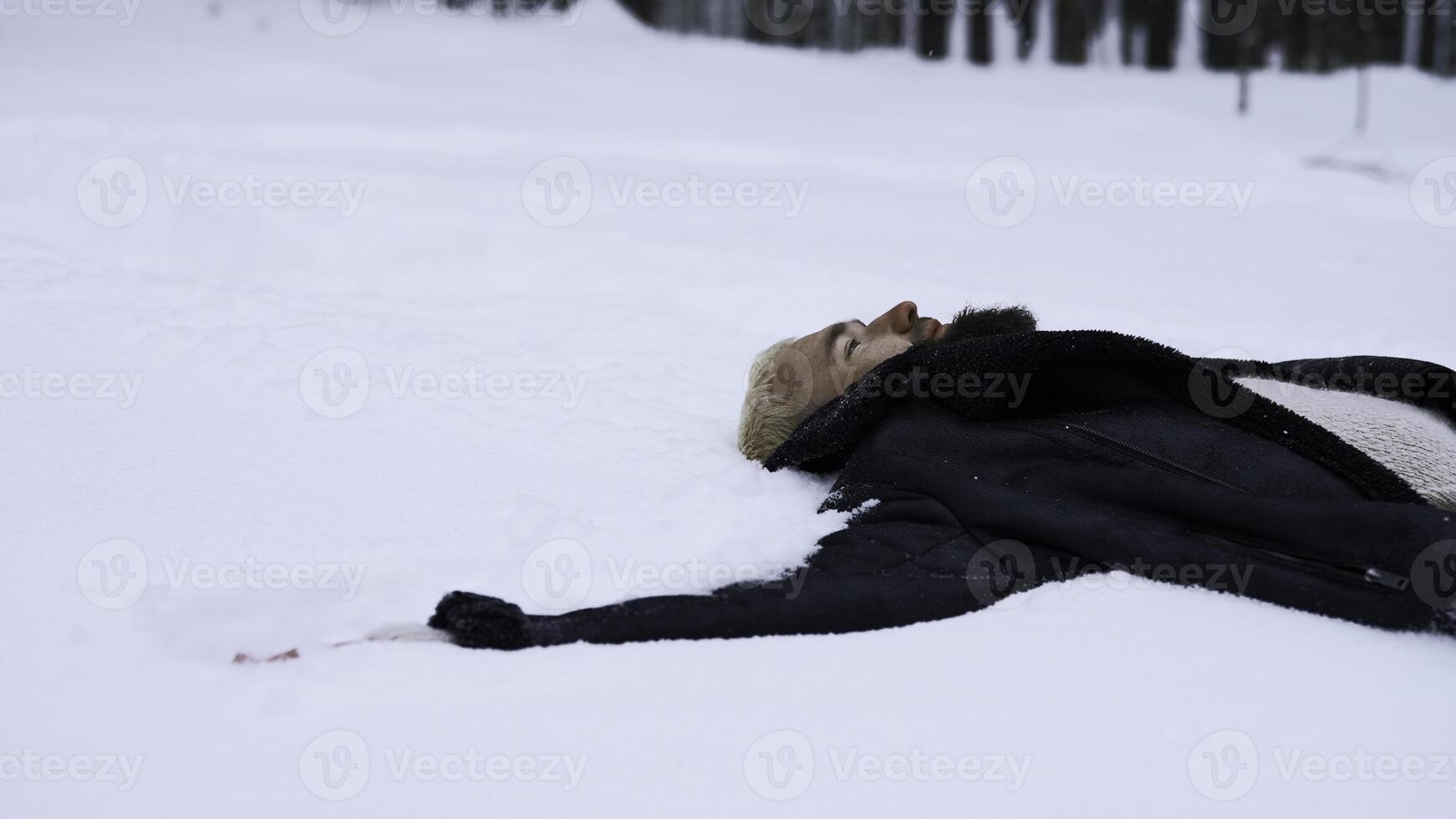 Happy young man in fairytale winter forest lying on snow. Media. Concept of religion and feeling unity with nature. photo