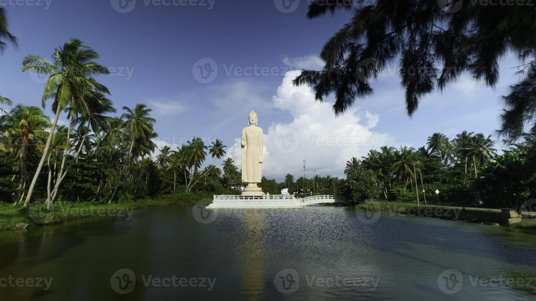 Tsunami Honganji Vihara, Hikkaduwa, Sri Lanka. Action. Beautiful white statue among green palm trees and blue cloudy sky. photo