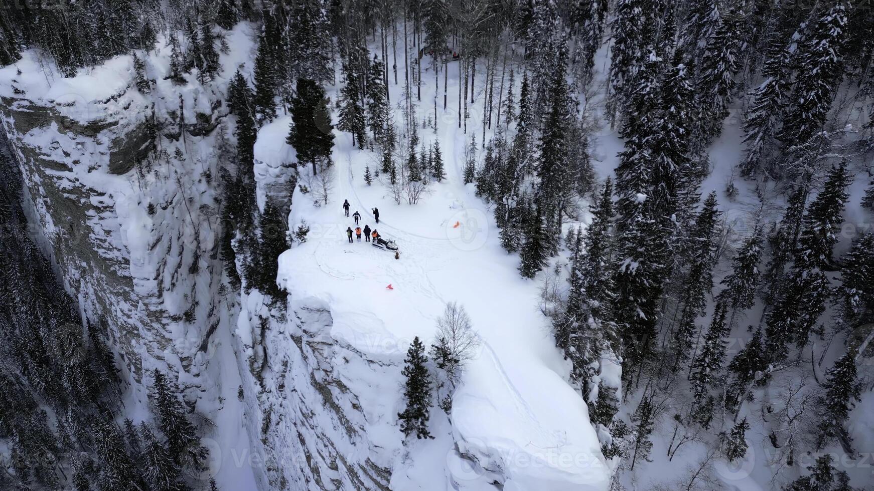 invierno montaña acantilado cubierto por nieve, hielo, y piel arboles acortar. maravilloso congelado invierno naturaleza, aéreo ver de turistas disfrutando el día en el acantilado borde. foto