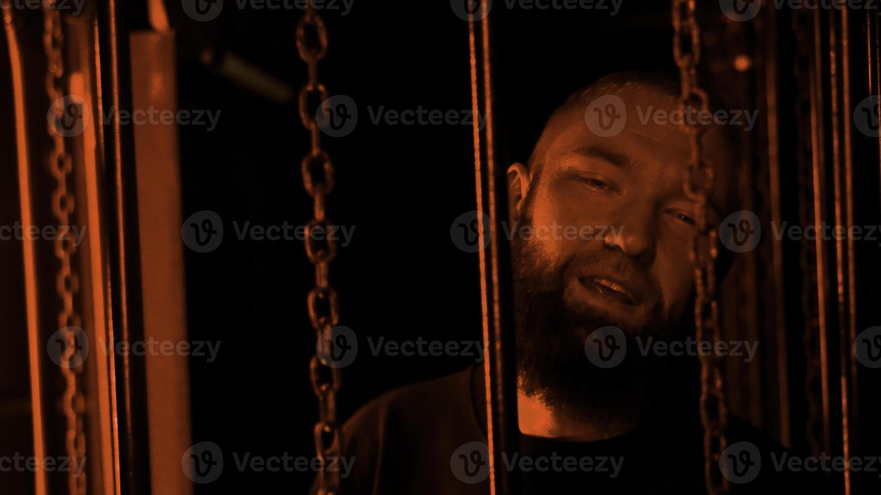 Stylish bearded man dancing by hanging chains in colorful neon light in night club. Media. Concept of rave night life. photo