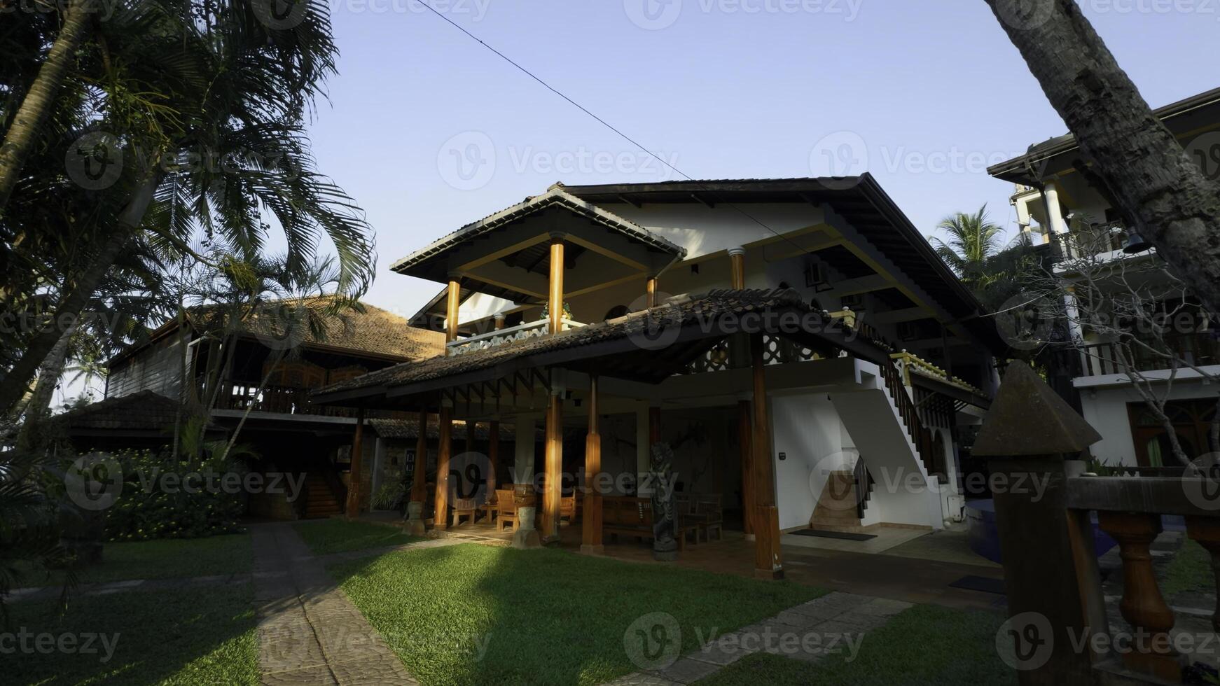 Luxury cottage with lush green bushes and long coconut trees. Action. Concept of summer vacation. photo