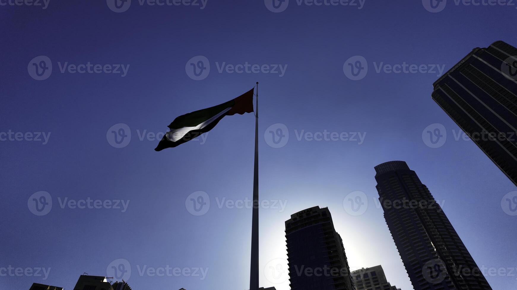 Low angle view of a waving flag against blue sky. Action. Dubai, UAE, architecture and waving flag. photo