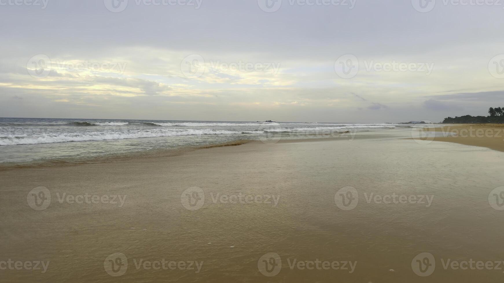 Beautiful landscape of sandy beach with long waves and blue cloudy sky. Action. Beautiful calm beach with in tropical island. photo