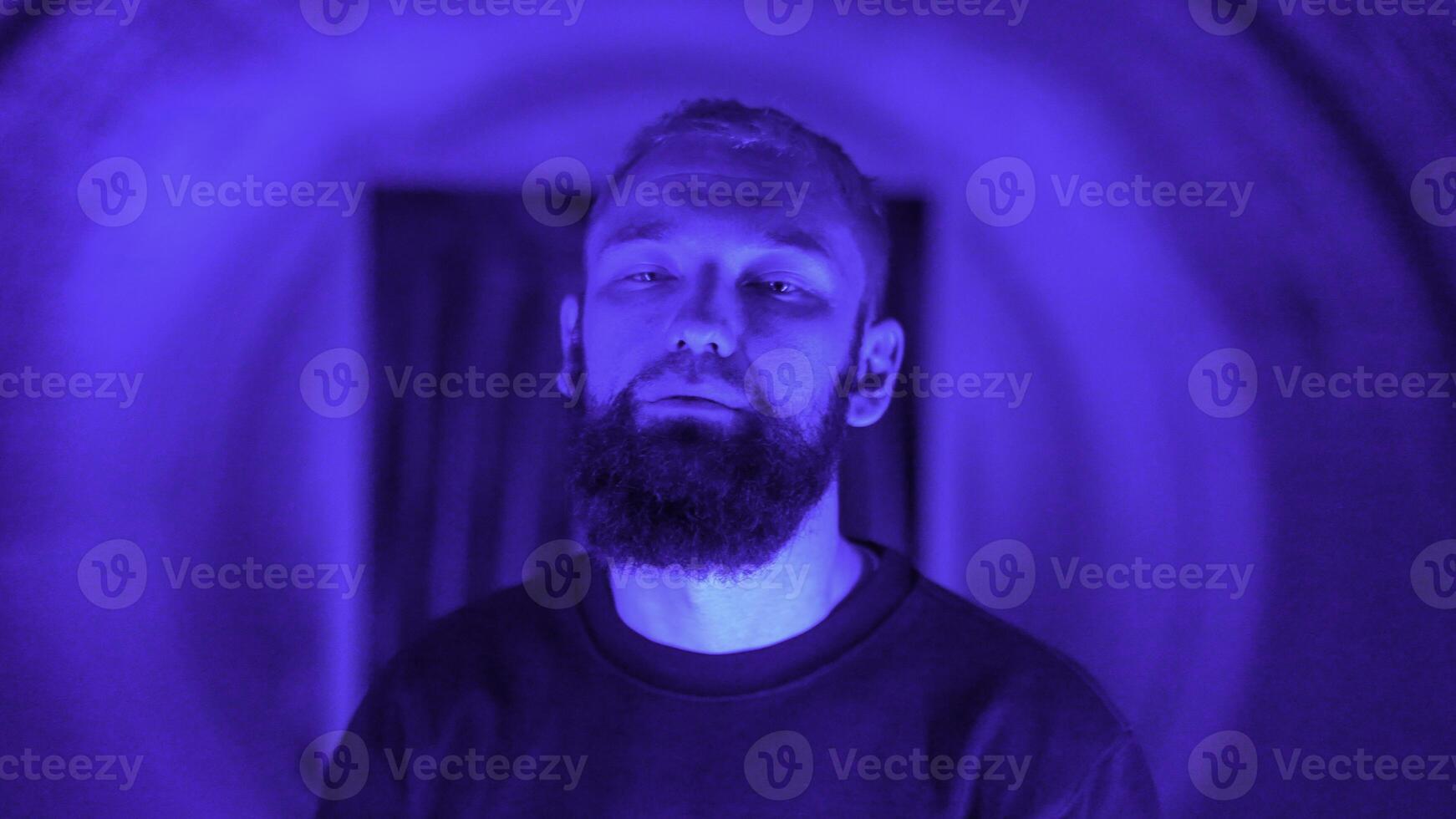 Portrait of a young stylish hipster man rapper moving and posing to the camera. Media. Neon lighting background creating effect of spinning tunnel. photo