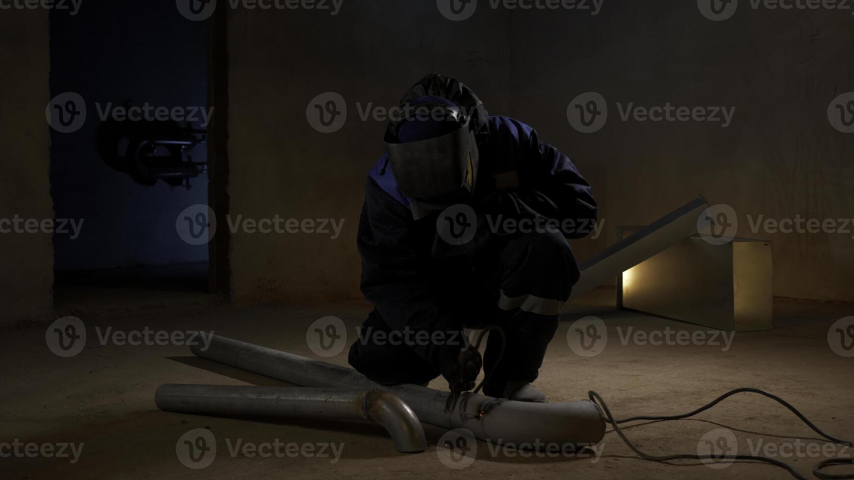 Worker welding metal pipe with many sparks are flying in different directions in the dark. Clip. Metalworking with hand-held power tools. photo