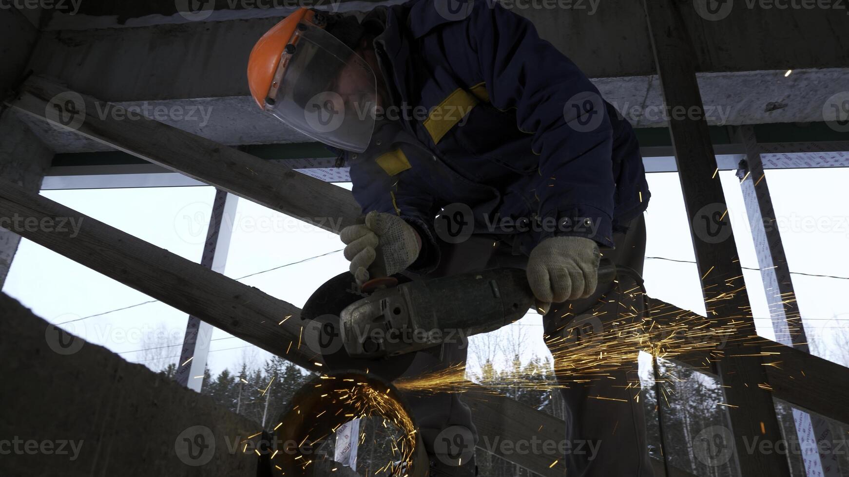 Worker welding metal pipe with many sparks are flying in different directions in the dark. Clip. Metalworking with hand-held power tools. photo