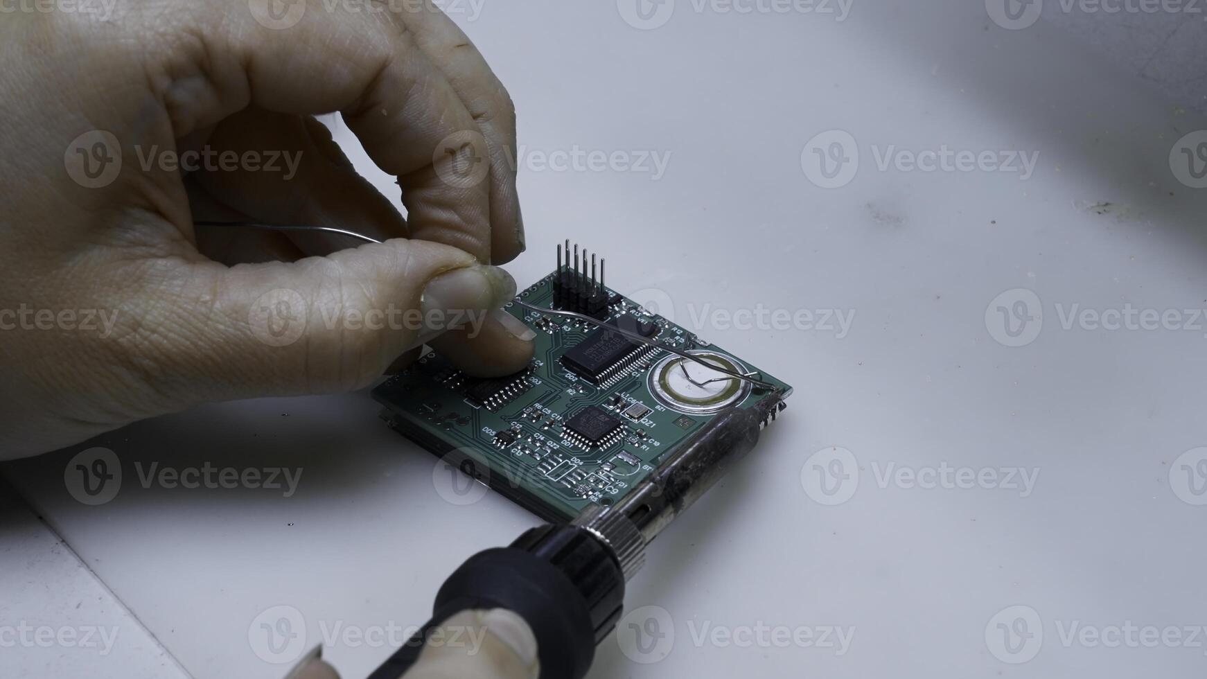 Close up of engineer does computer motherboard soldering. Creative. Painstaking work of soldering a chip. photo