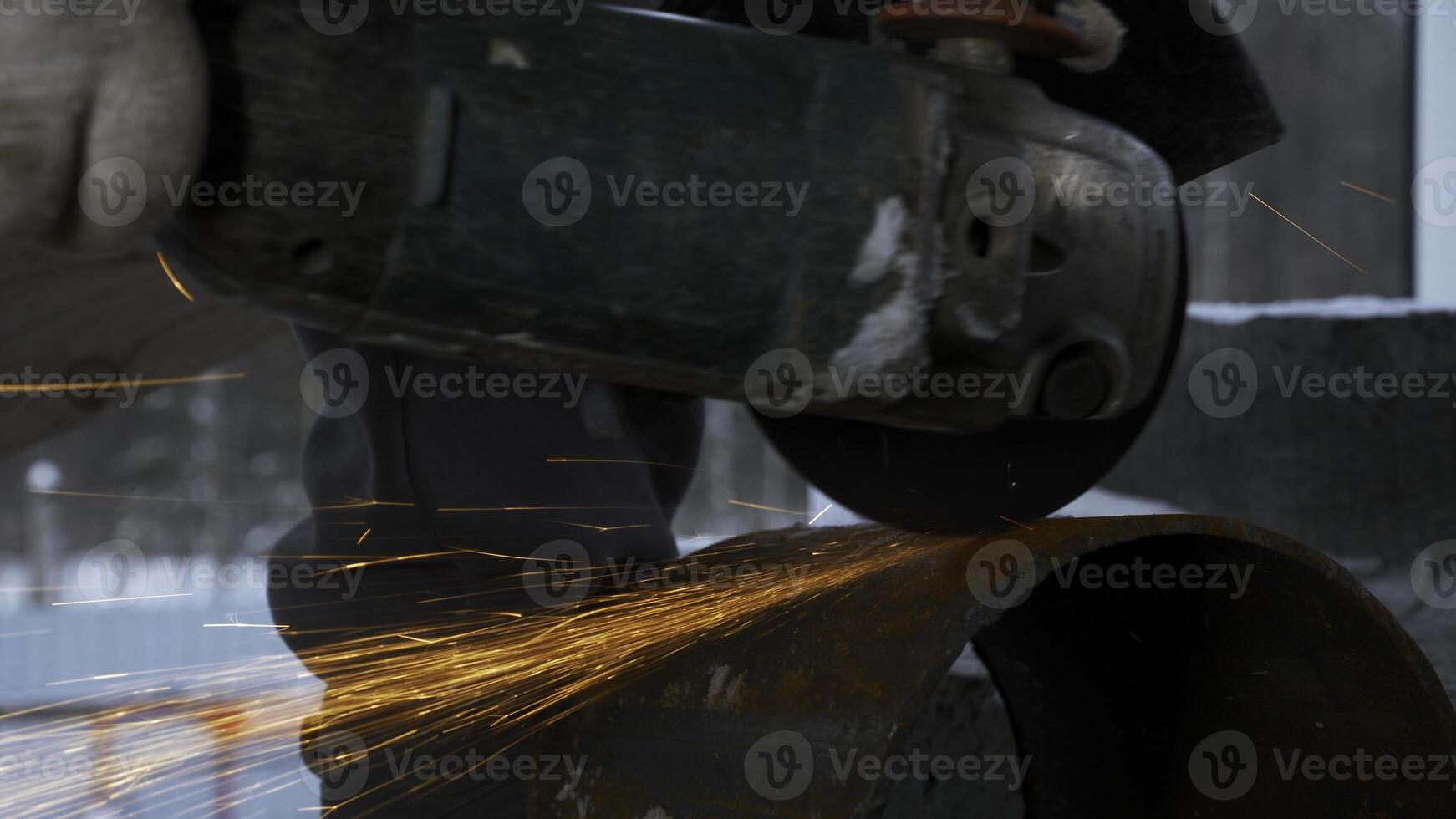 Man cutting metal piece of pipe with circular saw. Clip. Sparks fly from hot metal, man hard working over the steel. photo