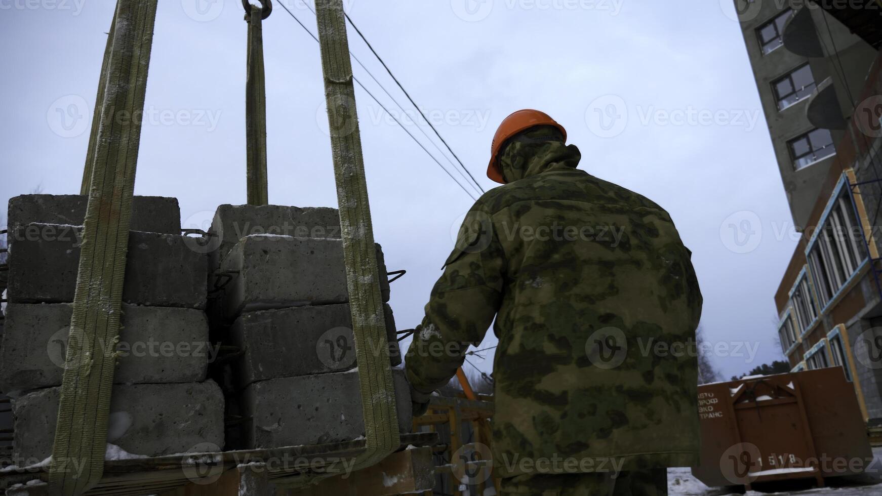 Transporting cement blocks by crane at the construction site. Clip. Builder and industrial background of a building. photo