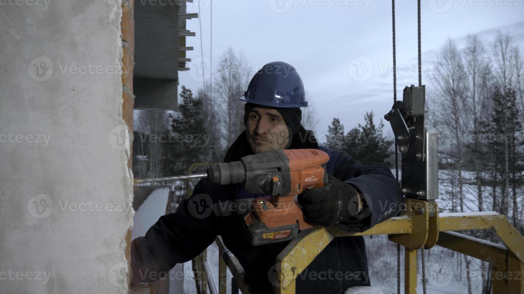 Man drills holes in a concrete wall. Clip. Industrial background of a builder at the construction site. photo