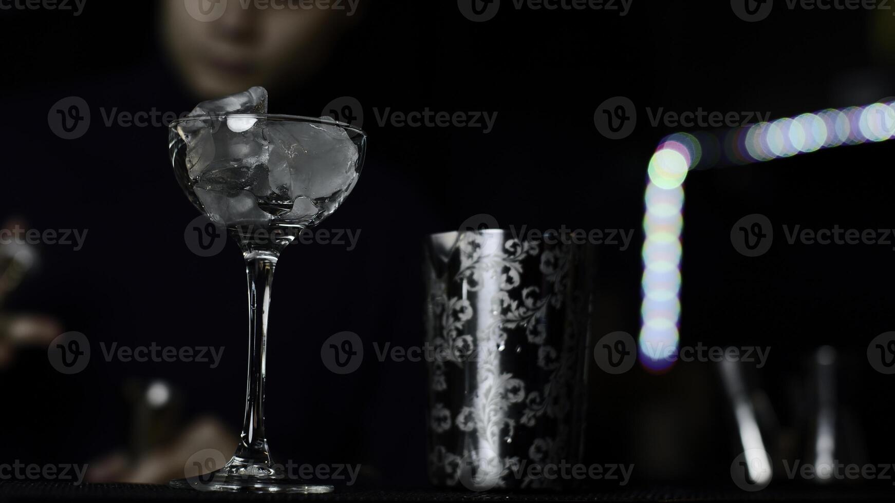 Close up of glass with ice cubes prepared for cocktail. Media. Bartender mixing alcohol liquids in a shaker. photo