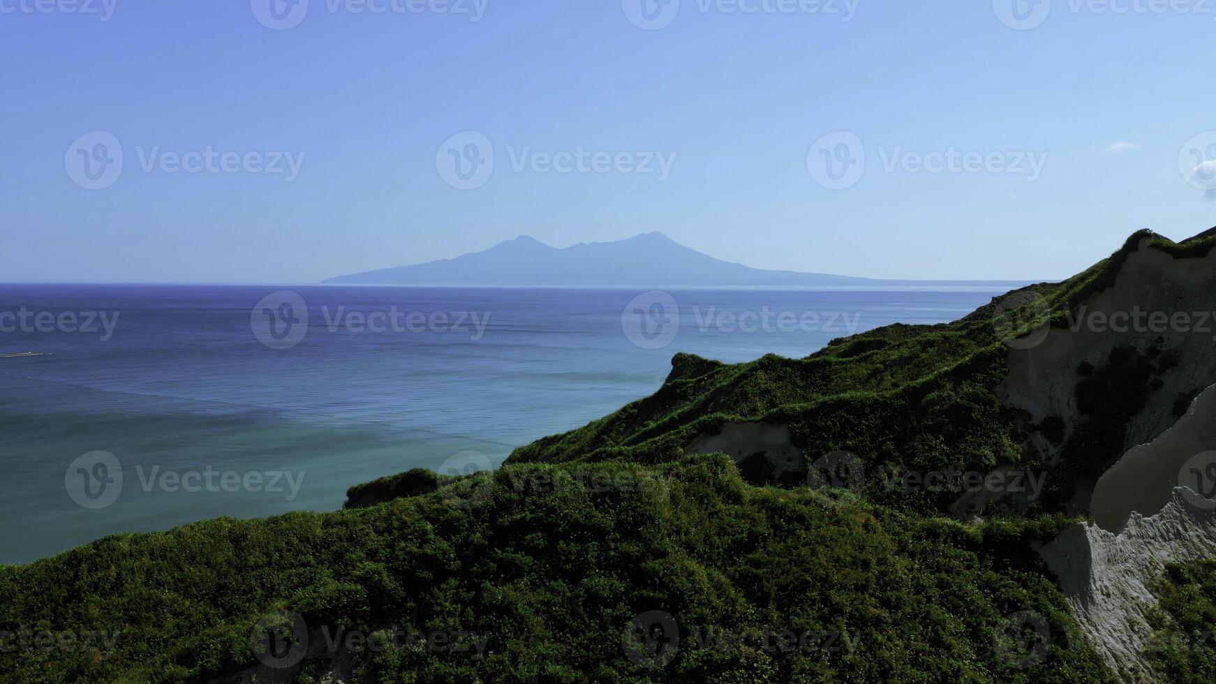 Breathtaking aerial view of dramatic green mountains and blue ocean. Clip. Beautiful nature background of green jungle mountain peaks revealing turquoise water surface. photo