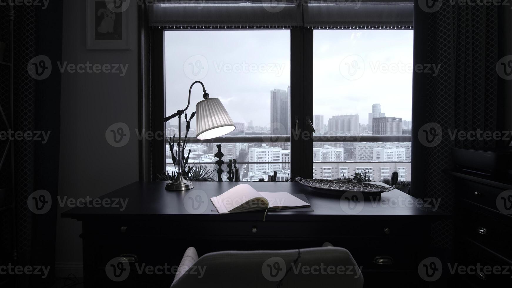 Cozy workplace at home. Creative. Table, book, and lamp in front of a window. photo