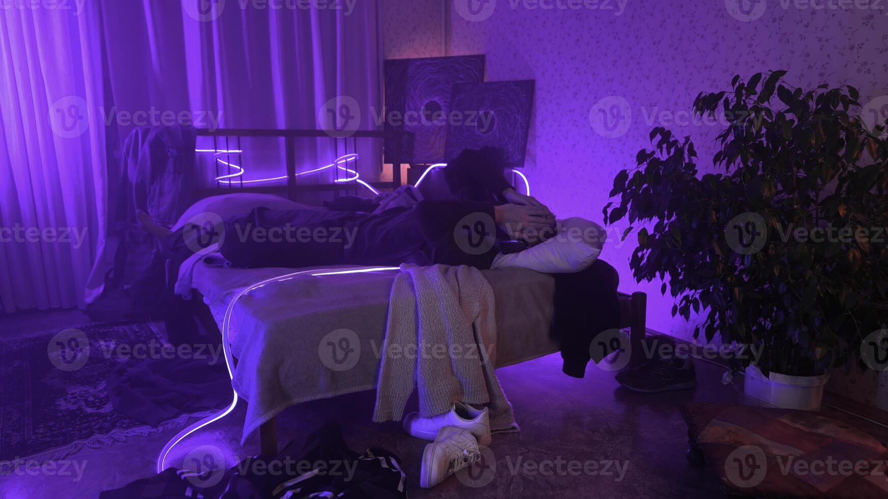 Man listening to music, using headphones in bedroom at night. Media. Man lying on his bed and enjoying music. photo