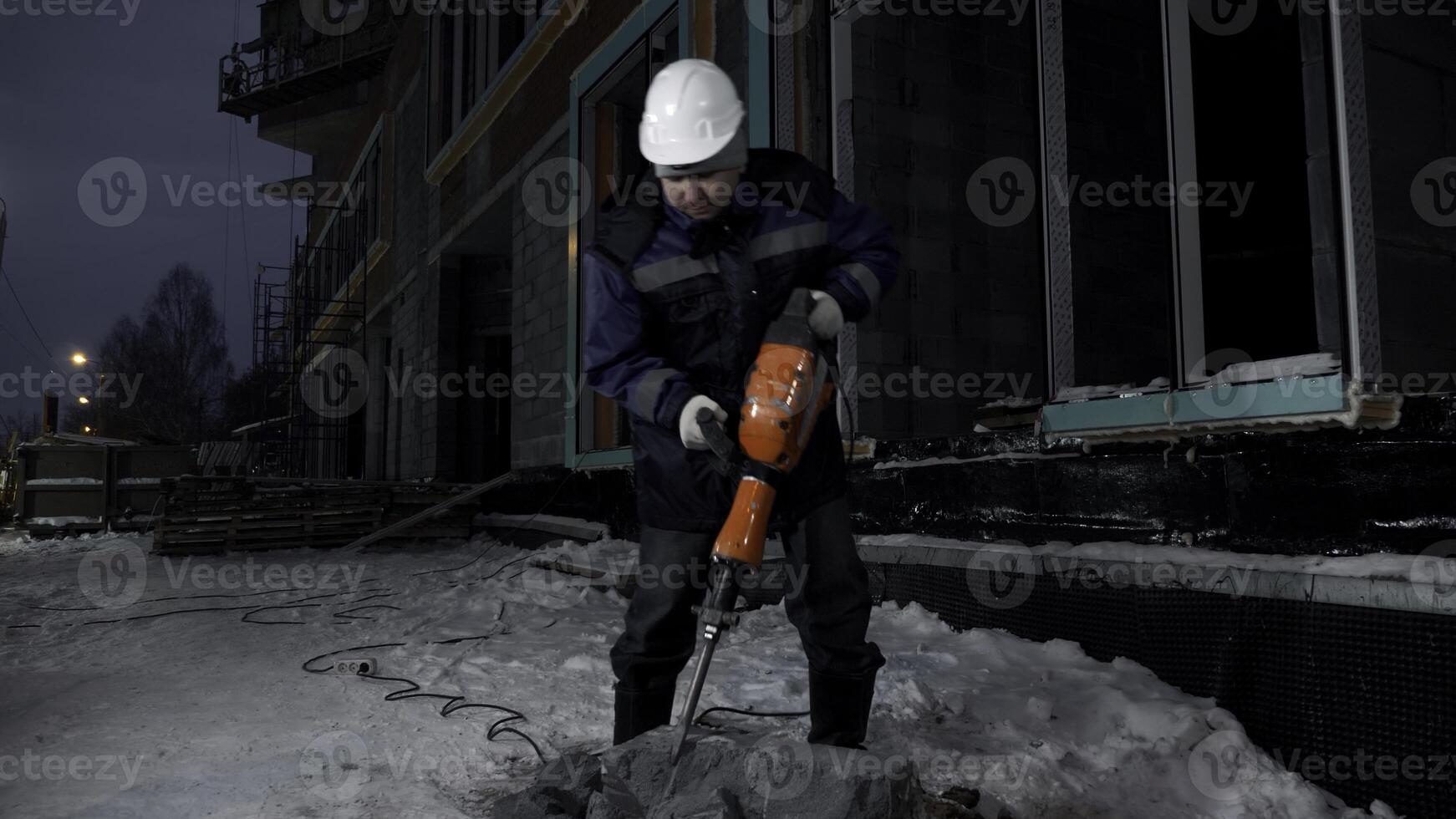 Construction worker uses hydraulic drill at construction site. Clip. Process of crashing a concrete block. photo