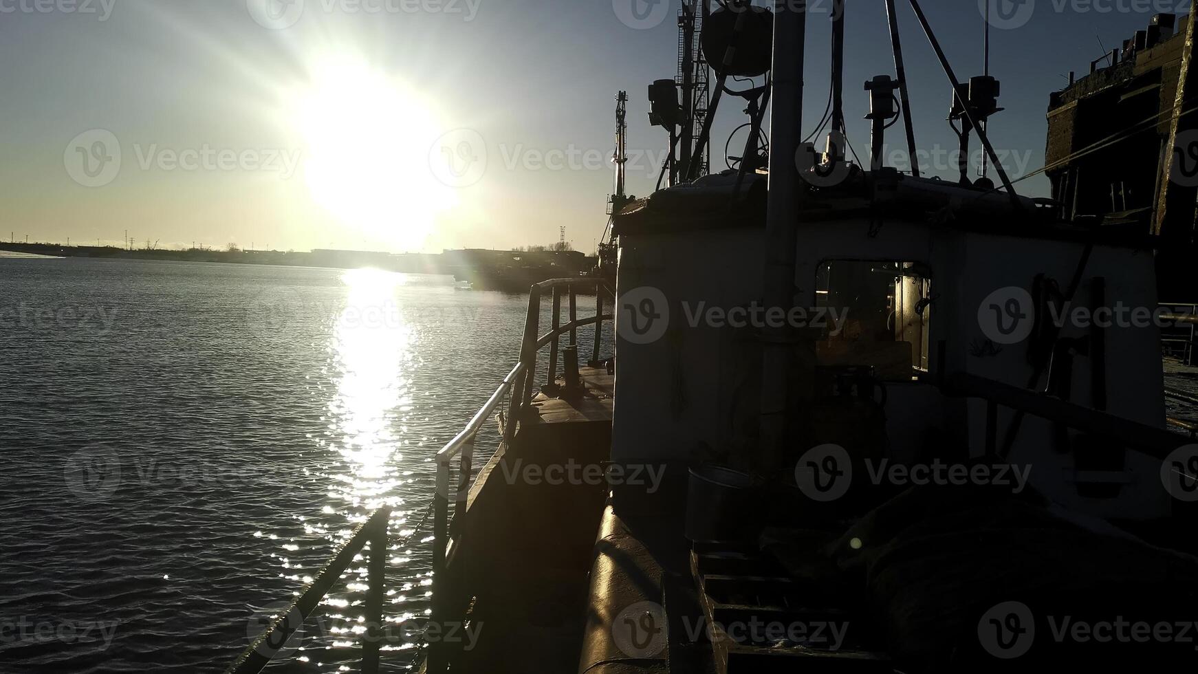 A view of a barge ship transporting goods. Clip. Ship on rippling river with shining sun on the background. photo