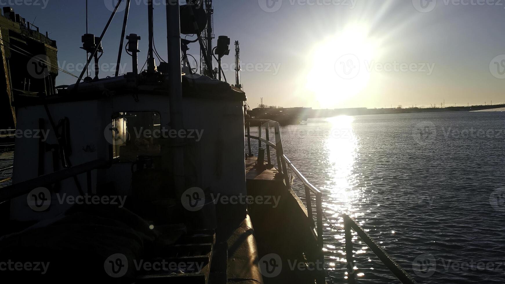 A view of a barge ship transporting goods. Clip. Ship on rippling river with shining sun on the background. photo