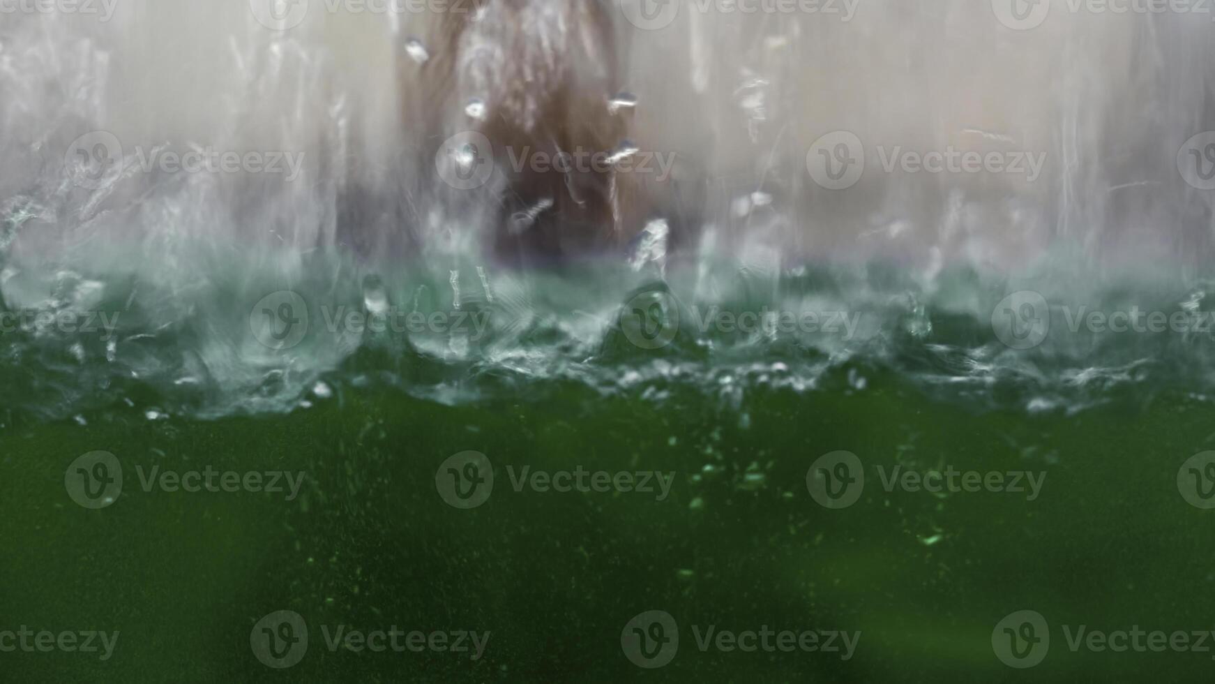 industrial background with a transparent reservoir being filled with liquid. Media. Water drops falling down and making ripples. photo