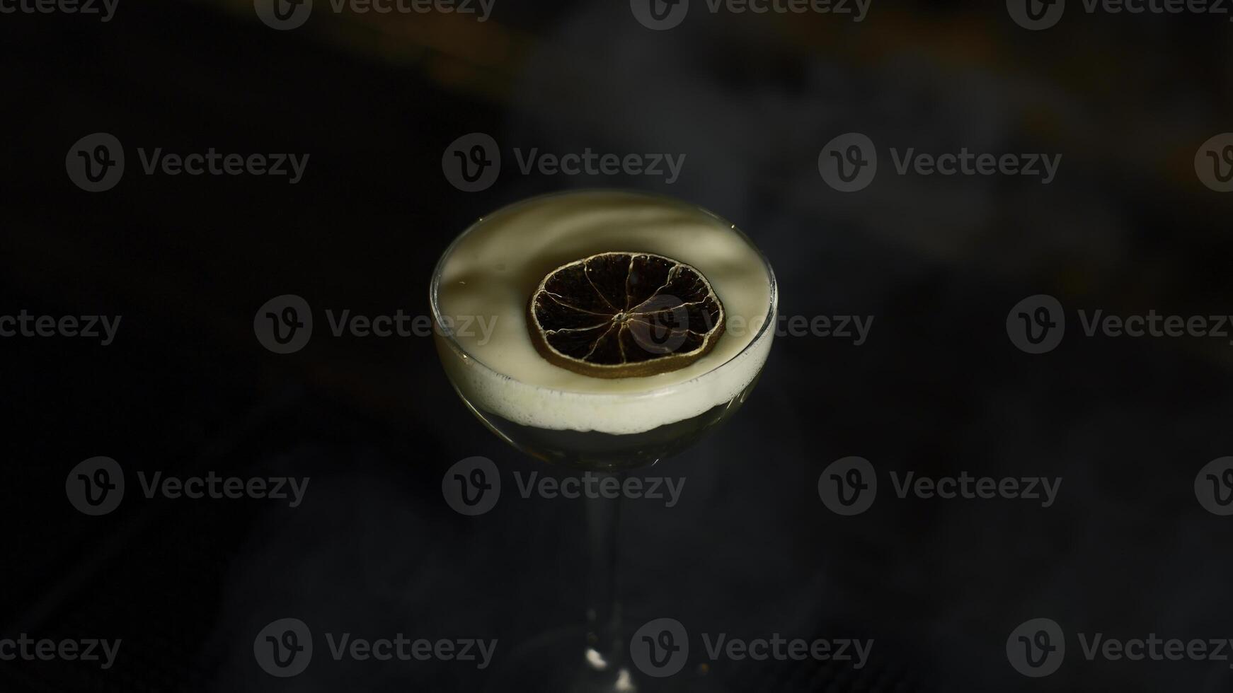 Close up of beautiful cocktail with thick foam and dried orange slice. Media. Beverage on bar counter background. photo