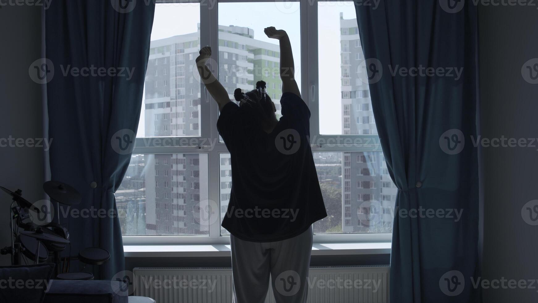 Relaxed lady stretching hands in the morning at home, back view. Media. Woman raising arms up enjoying new day after waking up. photo