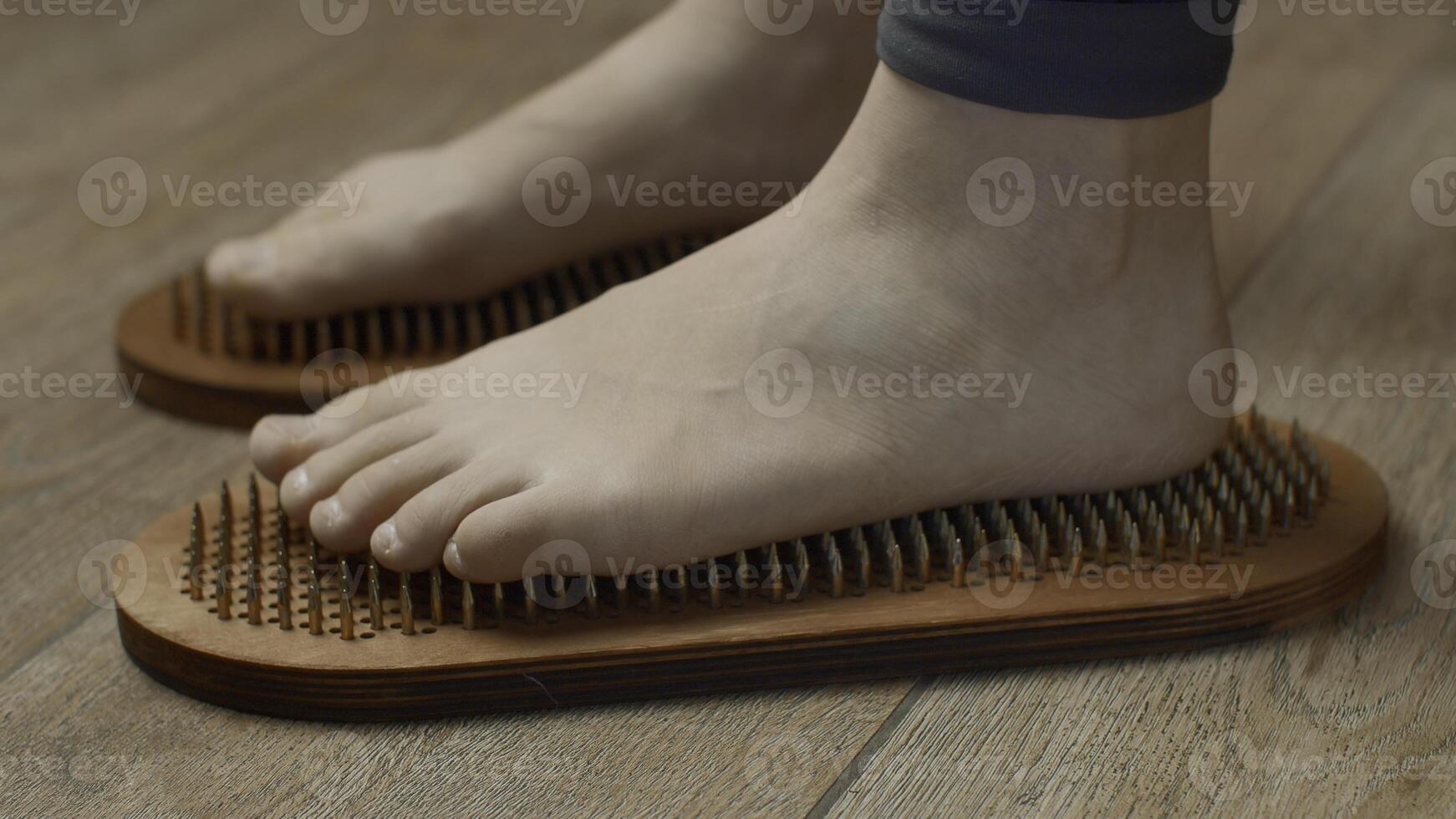 Female feet standing on boards with nails, close up. Media. Barefoot female standing on yoga nails board. photo