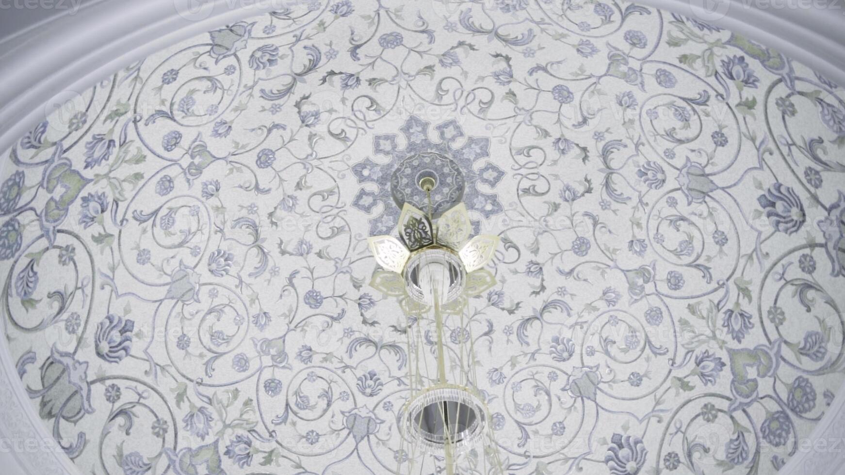 Decorative ceiling in a form of a dome with blue floral pattern. Scene. Hanging small chandelier, bottom view. photo