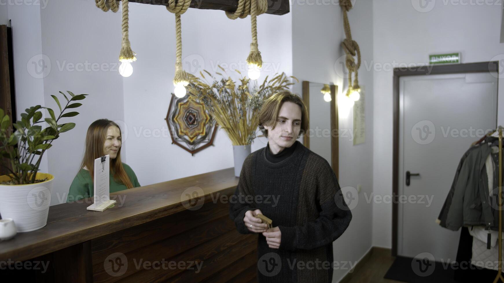 Young man check in at a hotel. Media. Happy receptionist giving a key to a man at the reception desk, concept of travelling. photo