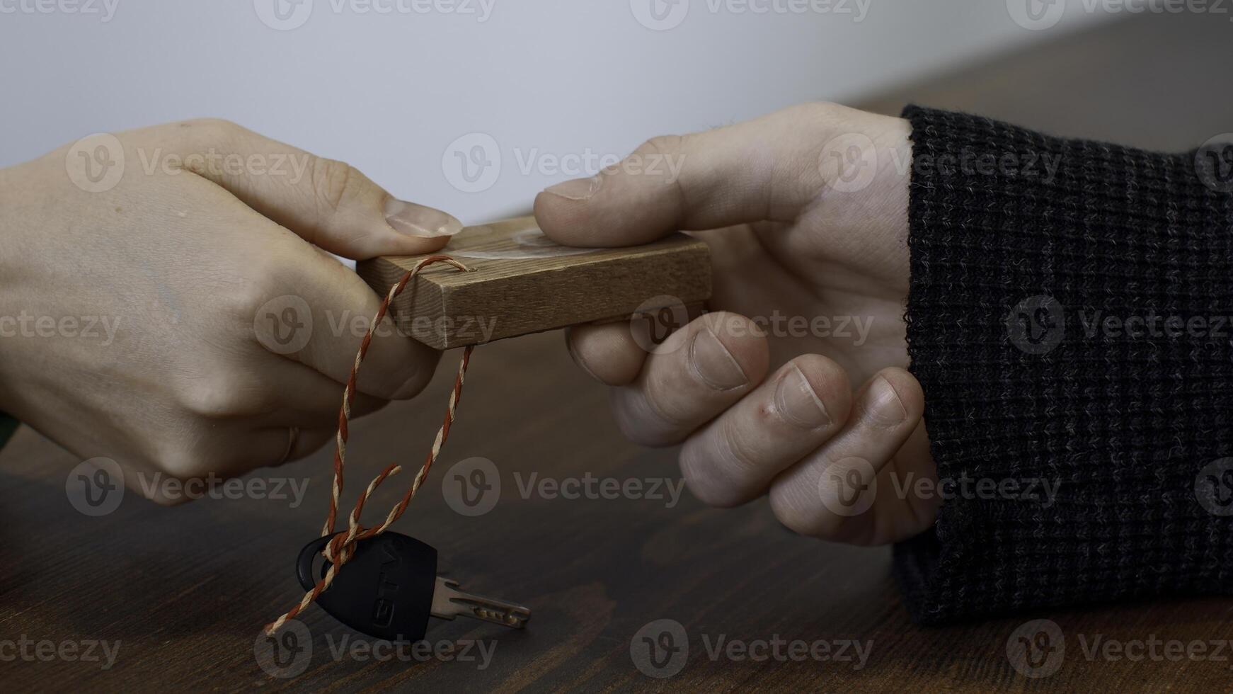 Passing small key with wooden number of a locker. Media. Close up of hands passing and taking a key. photo