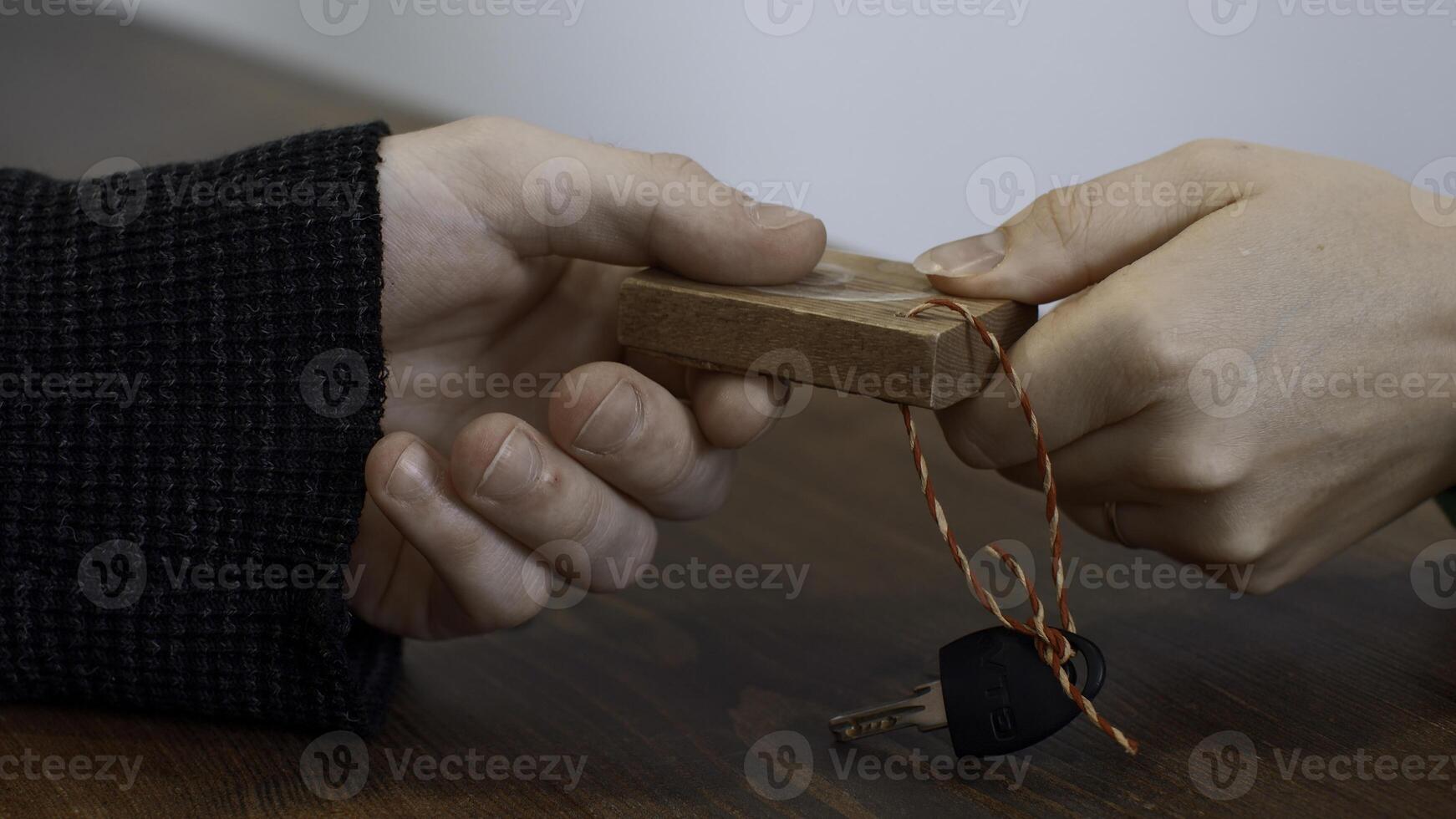 Close up of woman hand giving a key to a male hand on wooden desk background. Media. Taking a key at the fitness club reception. photo