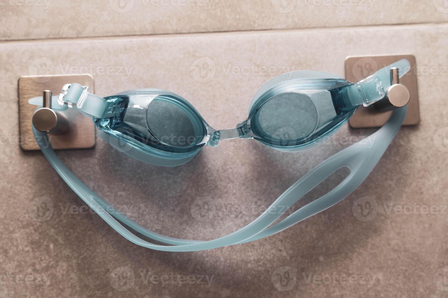 Swimming goggles displayed on a hook in the shower room interior photo
