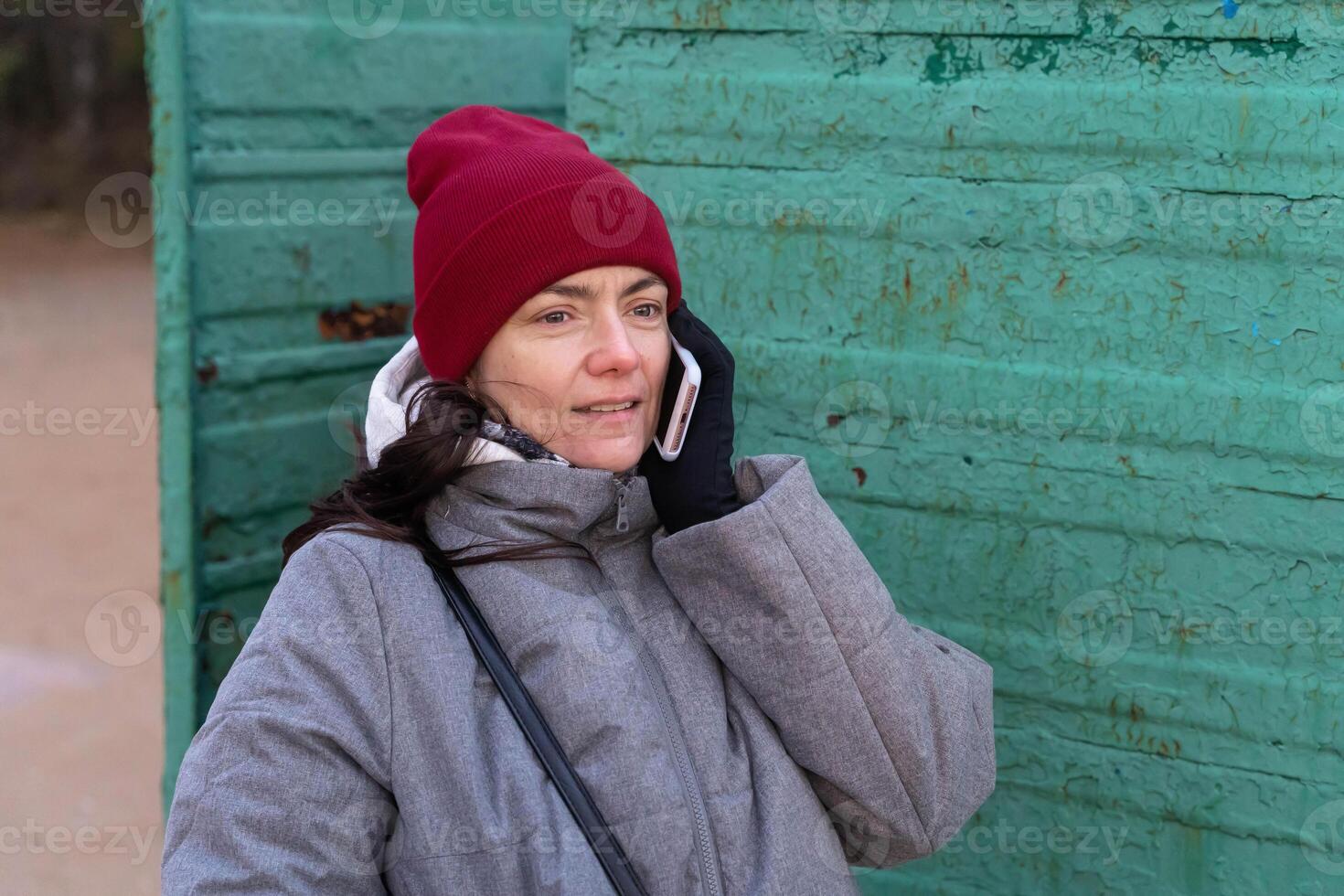 mujer en elegante otoño atuendo hablando en teléfono dentro Clásico cambiando cabina en playa foto