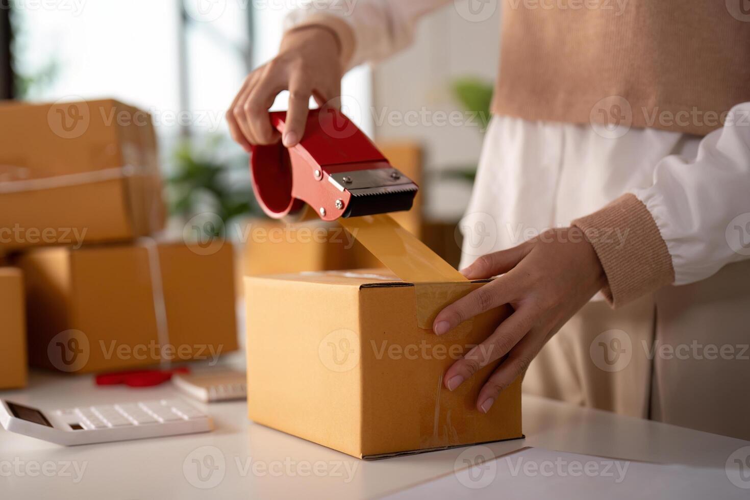 Woman asian use scotch tape to attach parcel boxes to prepare goods for the process of packaging, shipping, online sale internet marketing ecommerce concept startup business idea photo