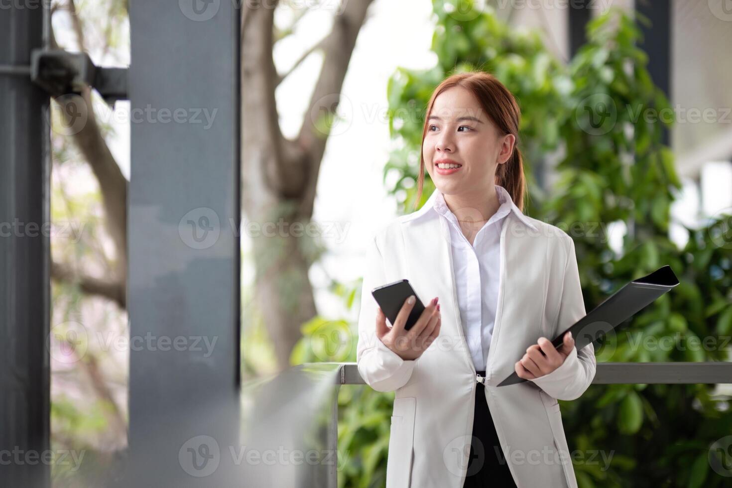 Asian business woman beautiful with smart phone and document file, asian woman with smartphone walking go to work. Preparation for the working day photo